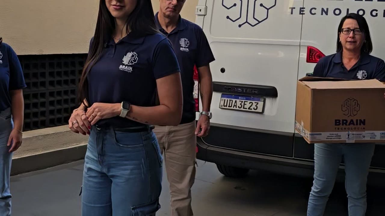 Equipe da Brain de uniforme carregando uma caixa da empresa para a entrega